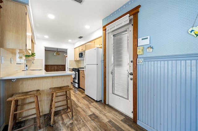 kitchen featuring appliances with stainless steel finishes, light brown cabinetry, sink, kitchen peninsula, and dark wood-type flooring