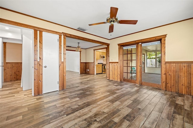 empty room featuring crown molding, wood-type flooring, and wood walls