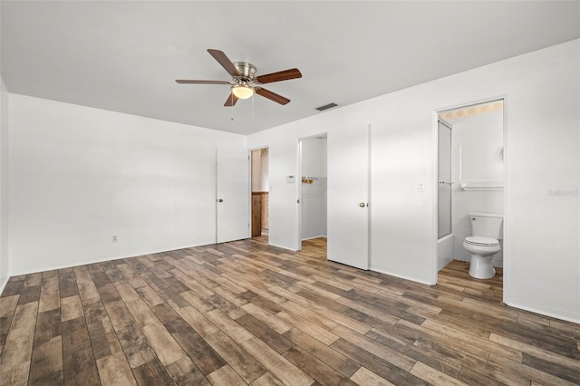 unfurnished bedroom featuring hardwood / wood-style flooring, ceiling fan, connected bathroom, a spacious closet, and a closet