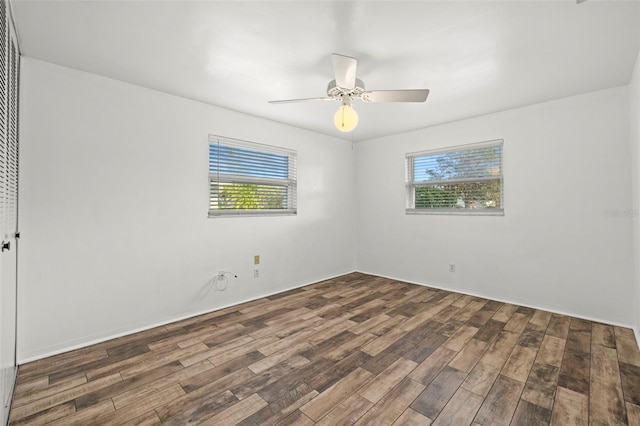 empty room with dark wood-type flooring, a wealth of natural light, and ceiling fan