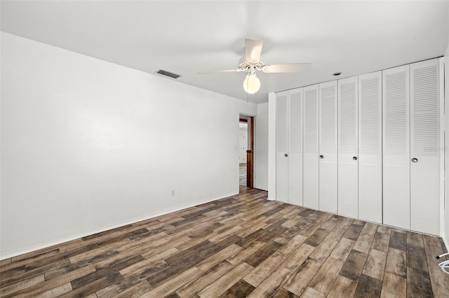 unfurnished bedroom with dark wood-type flooring, ceiling fan, and a closet