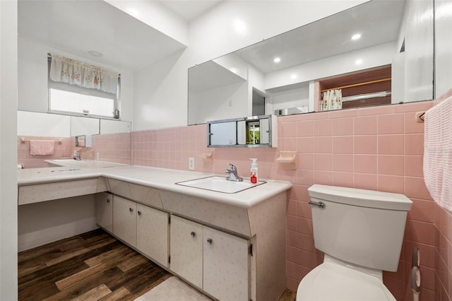 bathroom with vanity, toilet, hardwood / wood-style floors, and tile walls