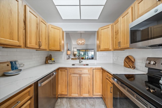 kitchen with pendant lighting, stainless steel appliances, sink, and backsplash