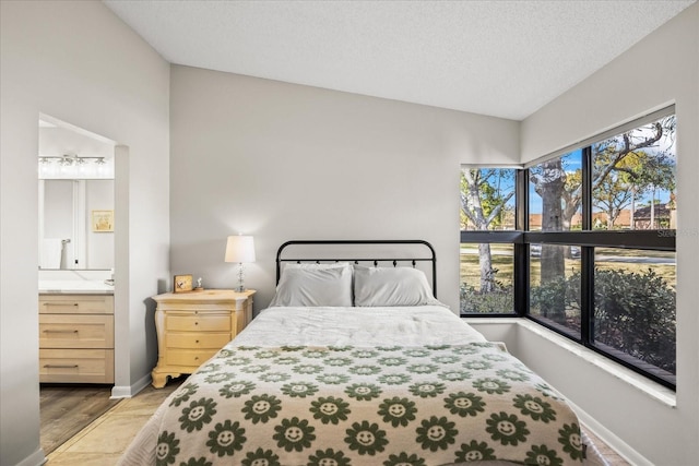 bedroom featuring light hardwood / wood-style flooring, a textured ceiling, and ensuite bathroom