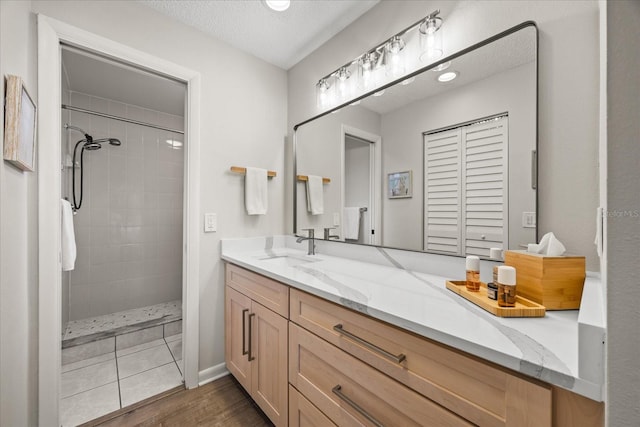 bathroom featuring vanity, a tile shower, and a textured ceiling