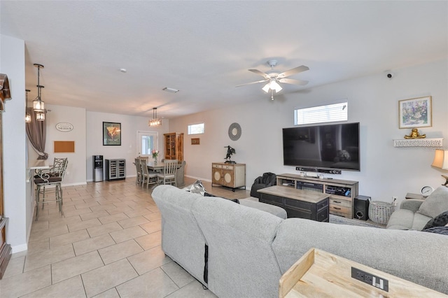 living room with plenty of natural light, a ceiling fan, light tile patterned floors, and baseboards