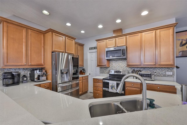kitchen featuring stainless steel appliances, a sink, decorative backsplash, recessed lighting, and brown cabinetry