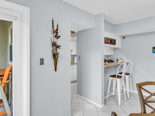 kitchen with white cabinetry, light tile patterned floors, and a textured ceiling