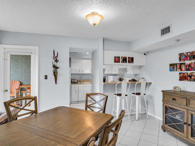 dining space featuring light tile patterned flooring and a textured ceiling