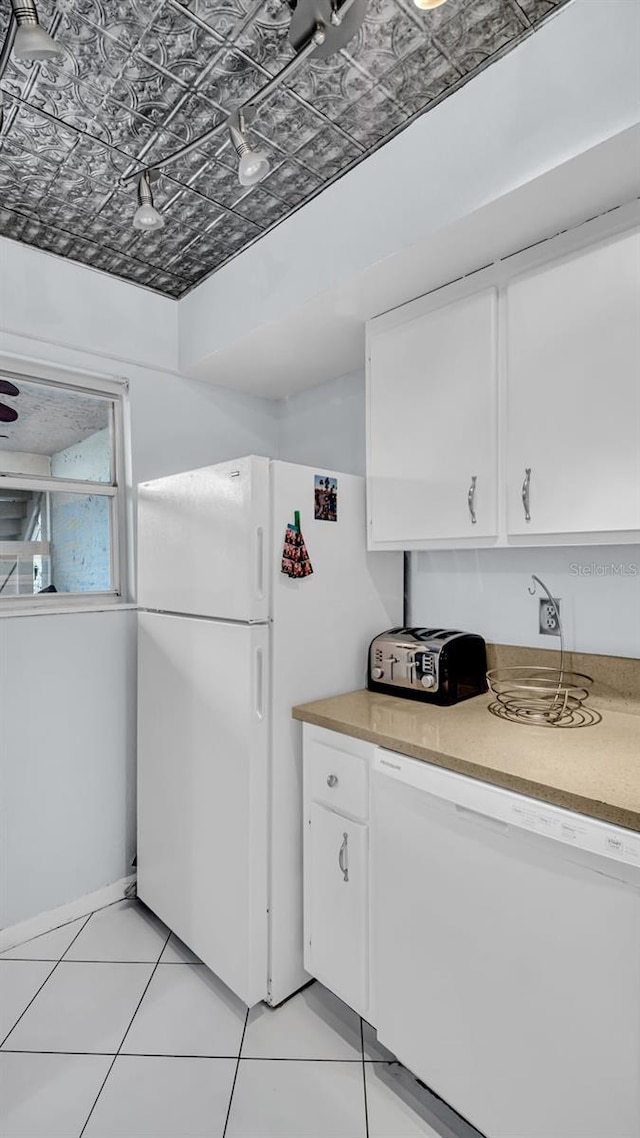 kitchen with light tile patterned floors, white cabinets, and white appliances