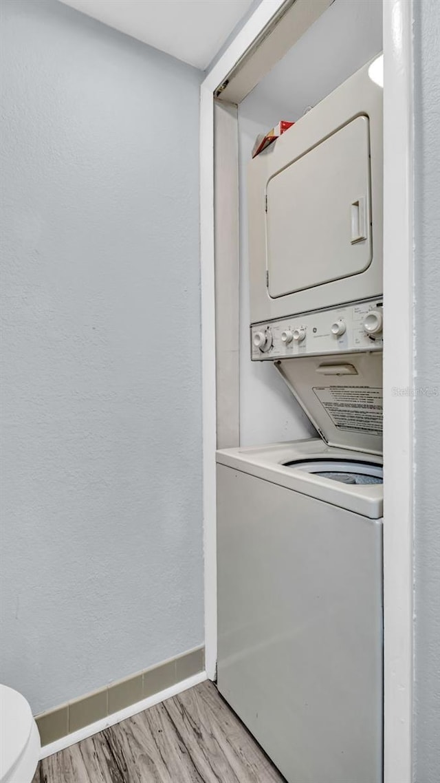 laundry room featuring stacked washer and clothes dryer and light hardwood / wood-style floors