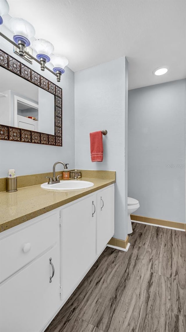 bathroom featuring vanity, wood-type flooring, and toilet