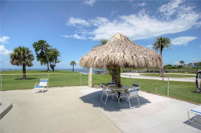 surrounding community with a patio, a water view, and a lawn