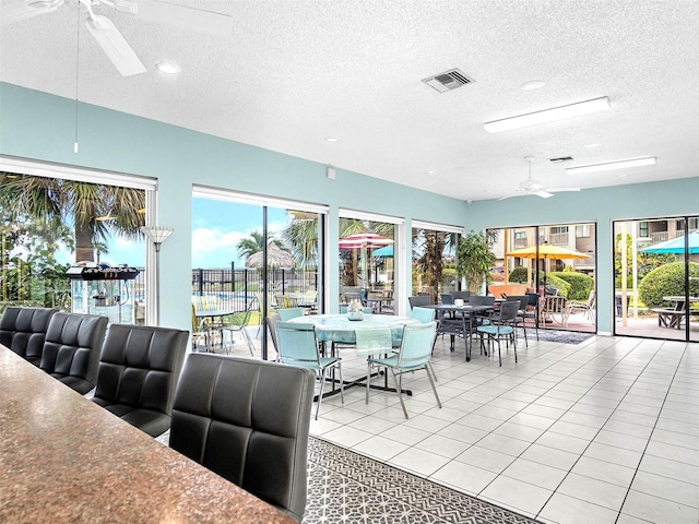 tiled dining space with plenty of natural light, a textured ceiling, and ceiling fan