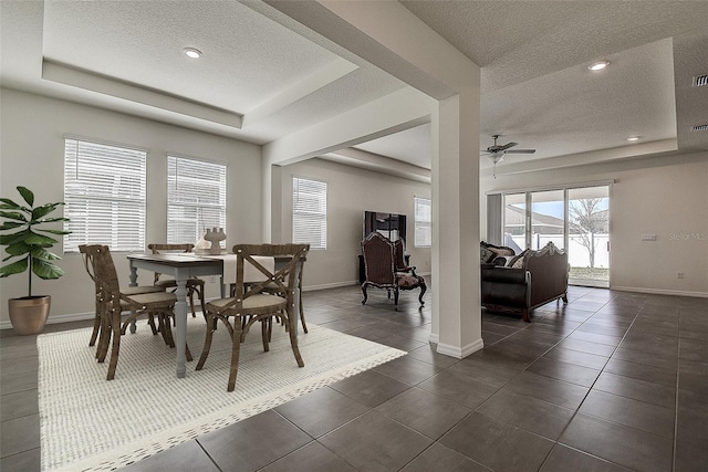 dining area featuring a textured ceiling, ceiling fan, a raised ceiling, and baseboards