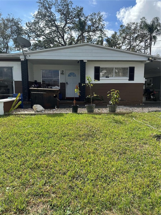 view of front of home featuring brick siding, an attached carport, and a front yard