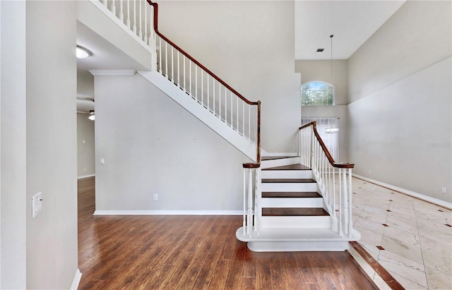 stairs with wood-type flooring and a towering ceiling