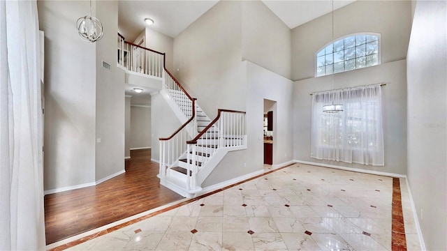 entrance foyer with hardwood / wood-style flooring, a chandelier, and a high ceiling