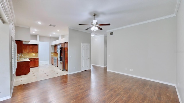 unfurnished living room with ceiling fan, ornamental molding, light hardwood / wood-style floors, and sink