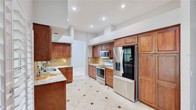 kitchen featuring sink, decorative backsplash, light stone countertops, and appliances with stainless steel finishes