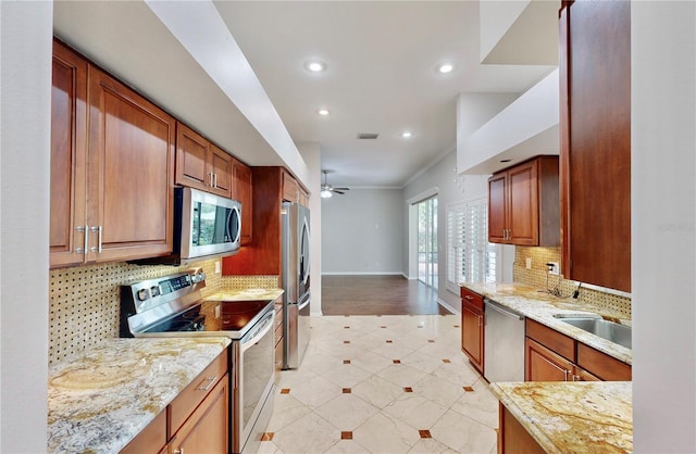 kitchen with sink, light stone counters, tasteful backsplash, ceiling fan, and stainless steel appliances