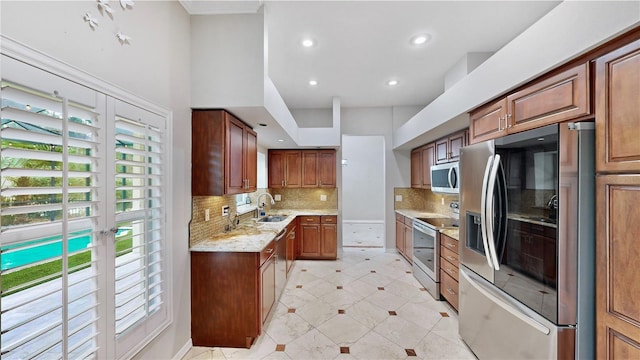 kitchen featuring sink, decorative backsplash, light stone countertops, and appliances with stainless steel finishes