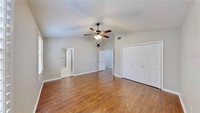 unfurnished bedroom with multiple windows, lofted ceiling, dark hardwood / wood-style flooring, and a closet