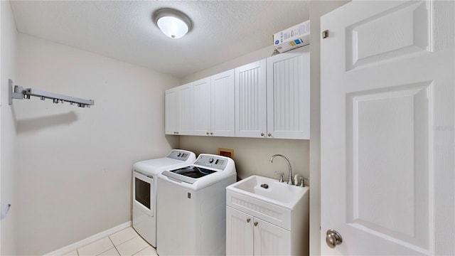 washroom featuring sink, light tile patterned floors, cabinets, a textured ceiling, and separate washer and dryer