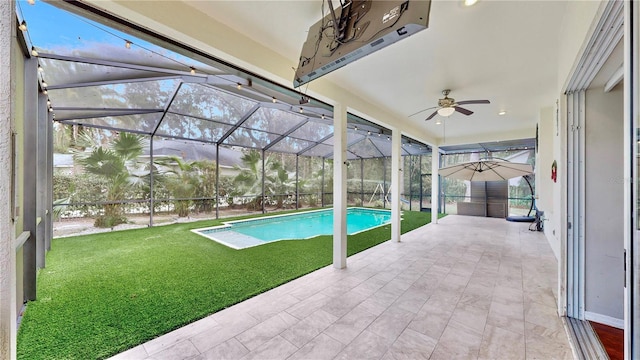 view of pool with a patio area, a lawn, ceiling fan, and glass enclosure