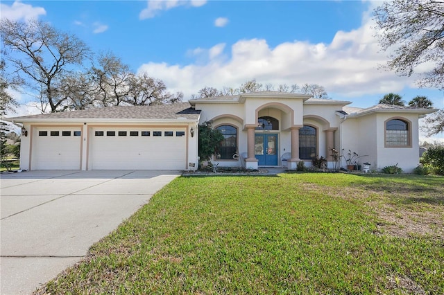 mediterranean / spanish-style home with a garage, a front yard, and french doors