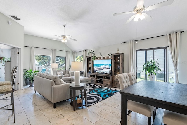 living room featuring ceiling fan, lofted ceiling, a textured ceiling, and light tile patterned floors