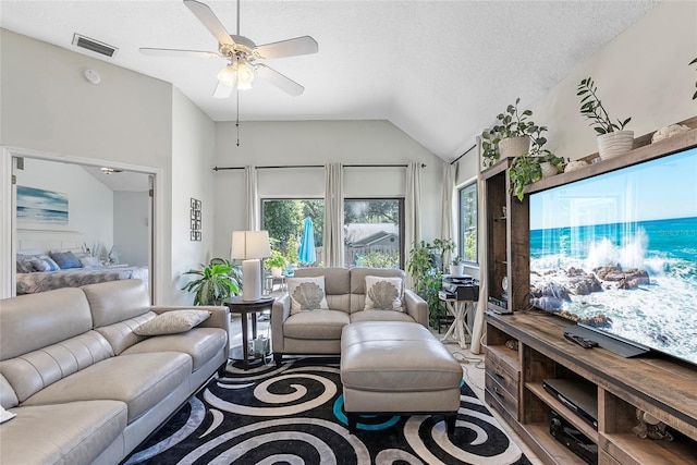 living room with ceiling fan, lofted ceiling, and a textured ceiling