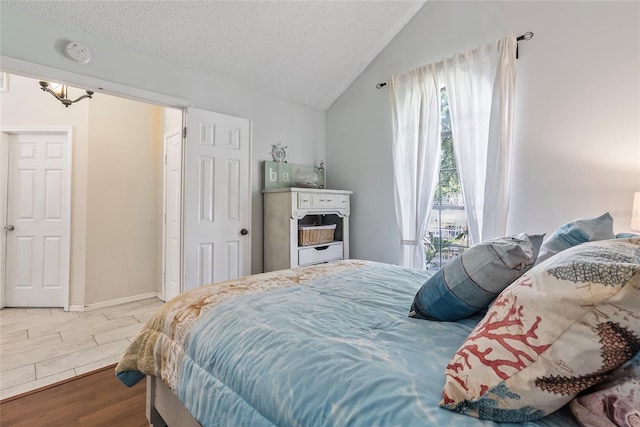 bedroom featuring hardwood / wood-style flooring, vaulted ceiling, and a textured ceiling