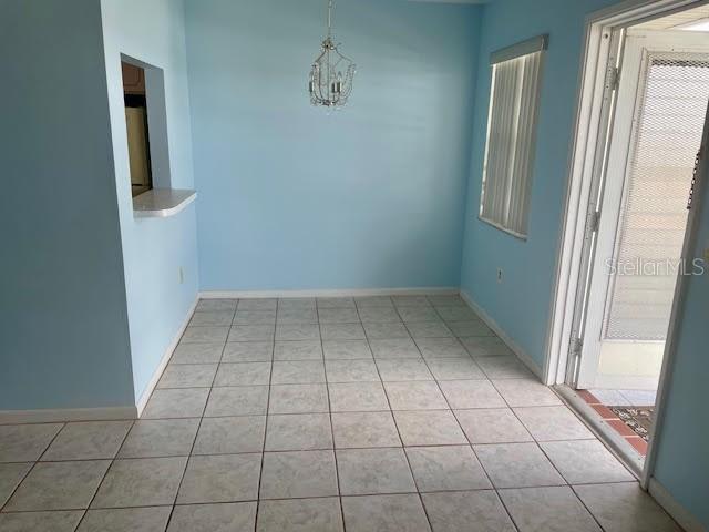 tiled empty room with a notable chandelier