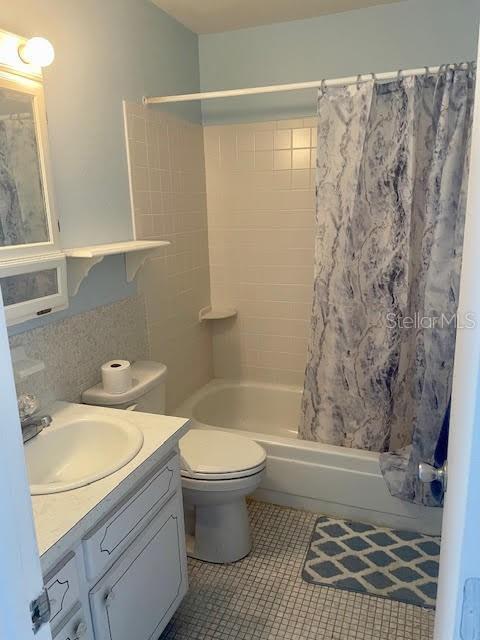 full bathroom with tile patterned flooring, shower / bath combo, vanity, and toilet