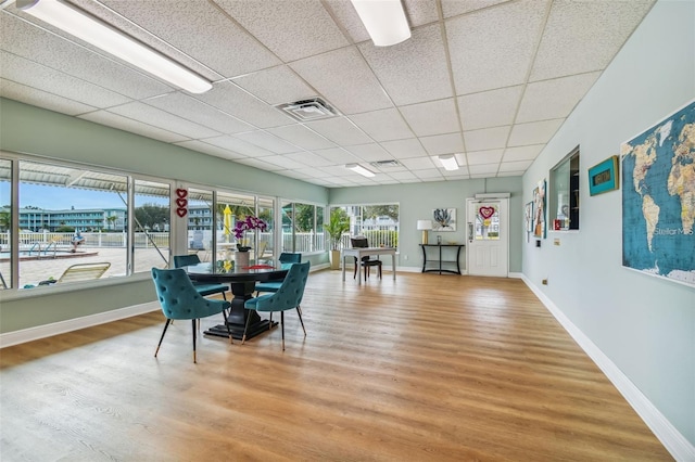 dining space featuring wood-type flooring and a paneled ceiling