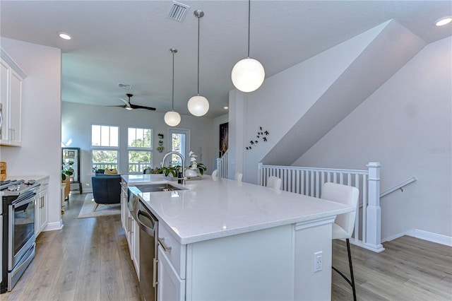 kitchen with white cabinetry, stainless steel appliances, a kitchen breakfast bar, and a center island with sink