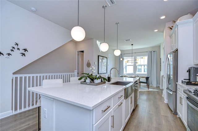 kitchen featuring white cabinetry, stainless steel appliances, a breakfast bar, and an island with sink