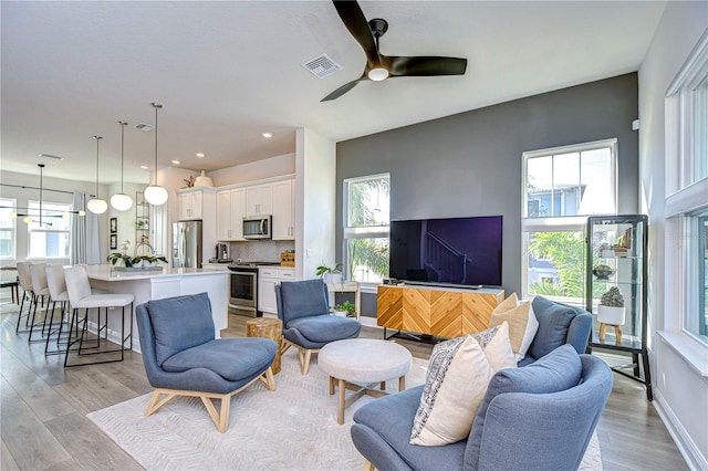 living room featuring ceiling fan, light hardwood / wood-style flooring, and a wealth of natural light