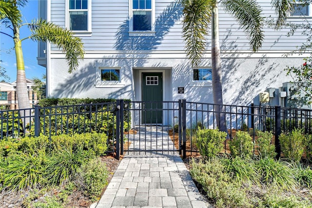 property entrance with a gate, fence, and stucco siding