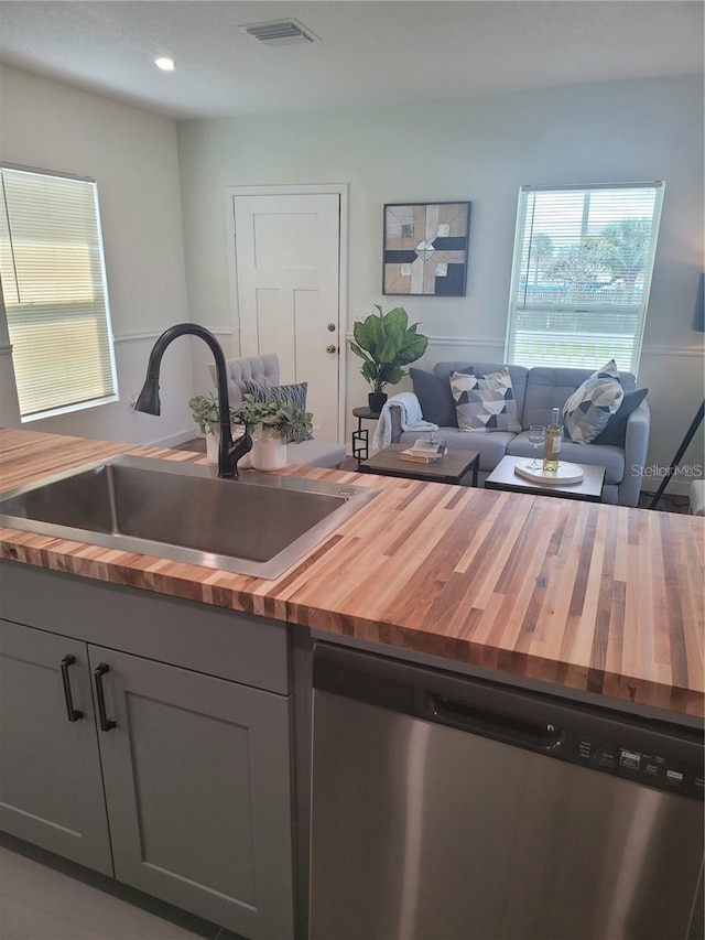 kitchen with gray cabinets, sink, stainless steel dishwasher, and wood counters