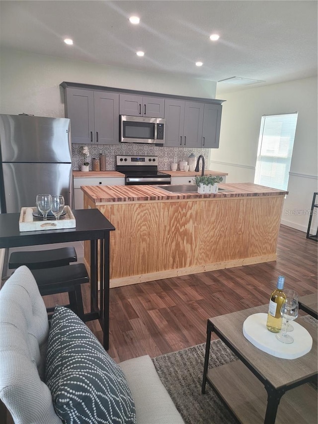 kitchen featuring gray cabinetry, backsplash, dark hardwood / wood-style floors, and appliances with stainless steel finishes