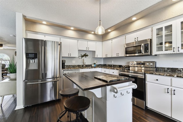 kitchen featuring pendant lighting, sink, appliances with stainless steel finishes, white cabinets, and a kitchen island