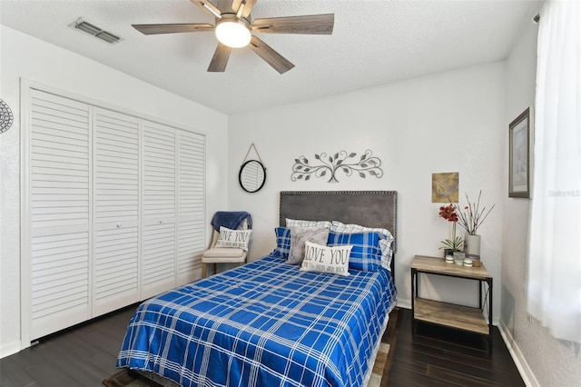 bedroom featuring dark wood-type flooring, a closet, ceiling fan, and a textured ceiling