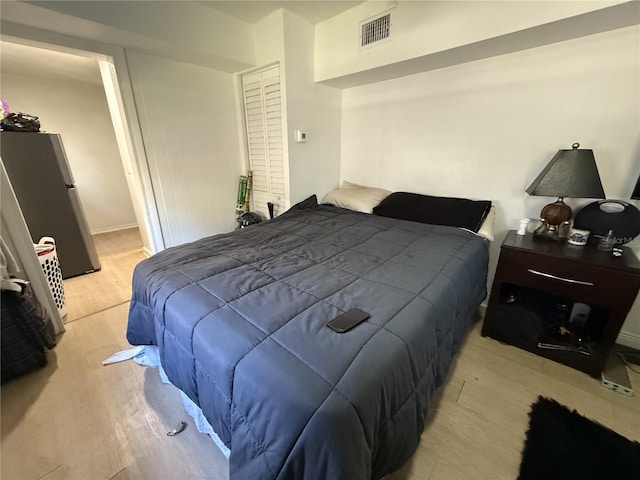 bedroom featuring stainless steel fridge and light wood-type flooring