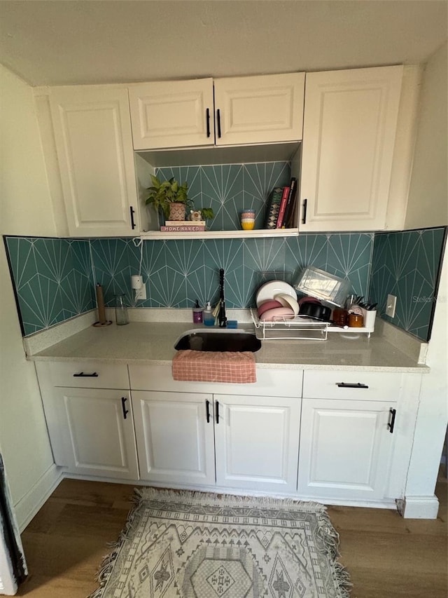 bar featuring white cabinetry, sink, hardwood / wood-style floors, and decorative backsplash