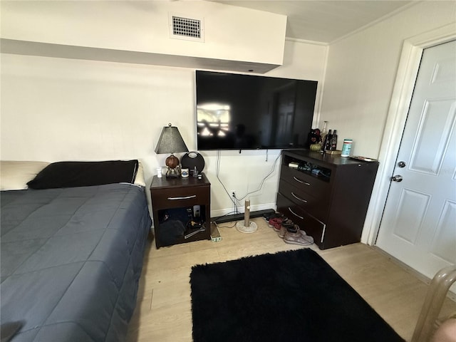 bedroom with ornamental molding and light hardwood / wood-style floors