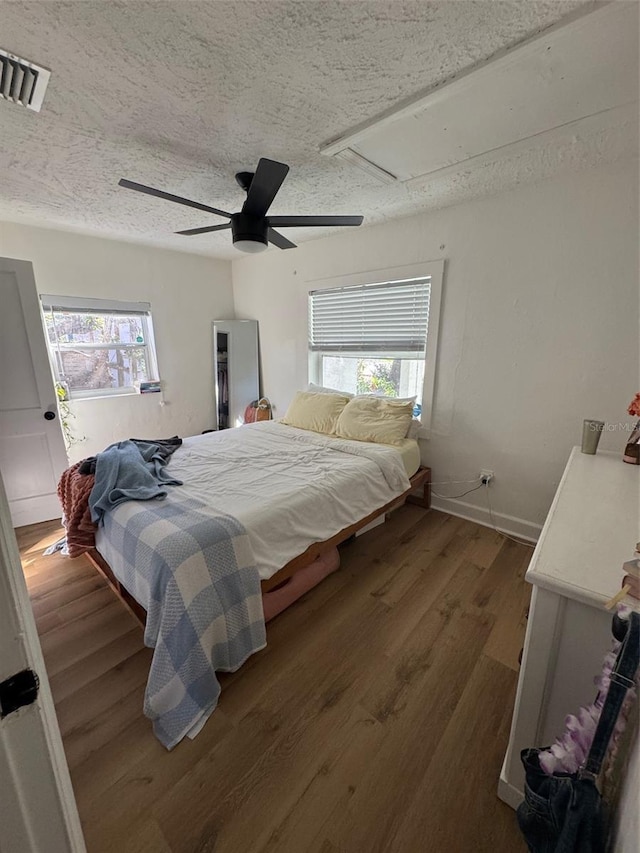 bedroom featuring ceiling fan, hardwood / wood-style floors, and a textured ceiling