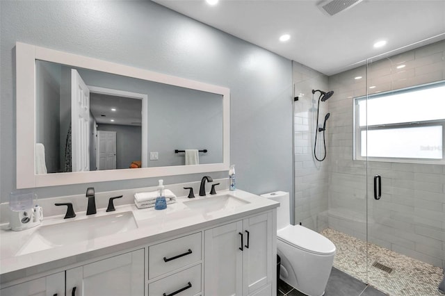 bathroom with a shower with door, vanity, tile patterned flooring, and toilet