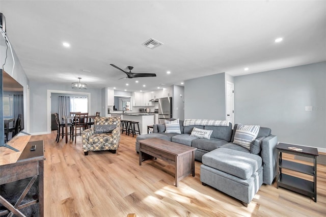 living room with ceiling fan, sink, and light hardwood / wood-style flooring